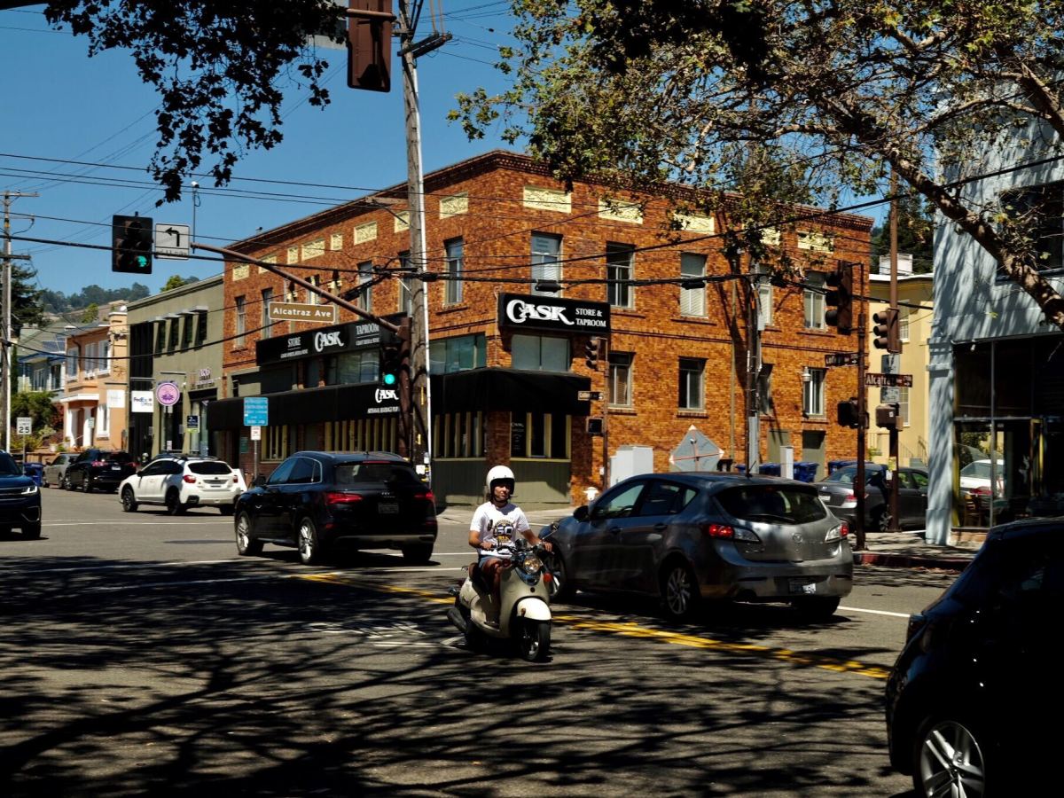 Cars and a motorcyclist pass through the intersection of College and Alcatraz in Southeast Berkeley