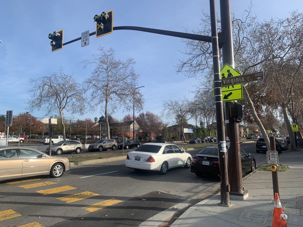 Cars pass through the intersection of Virginia Street and San Pablo Avenue in Berkeley. A stoplight hangs over the intersection, but it is covered by yellow tape because the signal hasn't been activated.