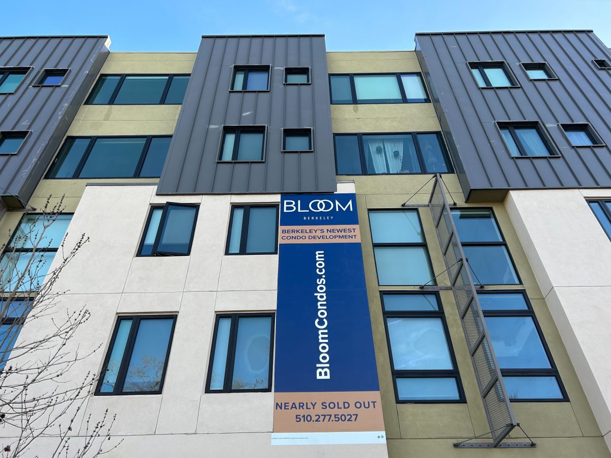 The exterior of a five-story condo building in West Berkeley, with a sign advertising units for sale.