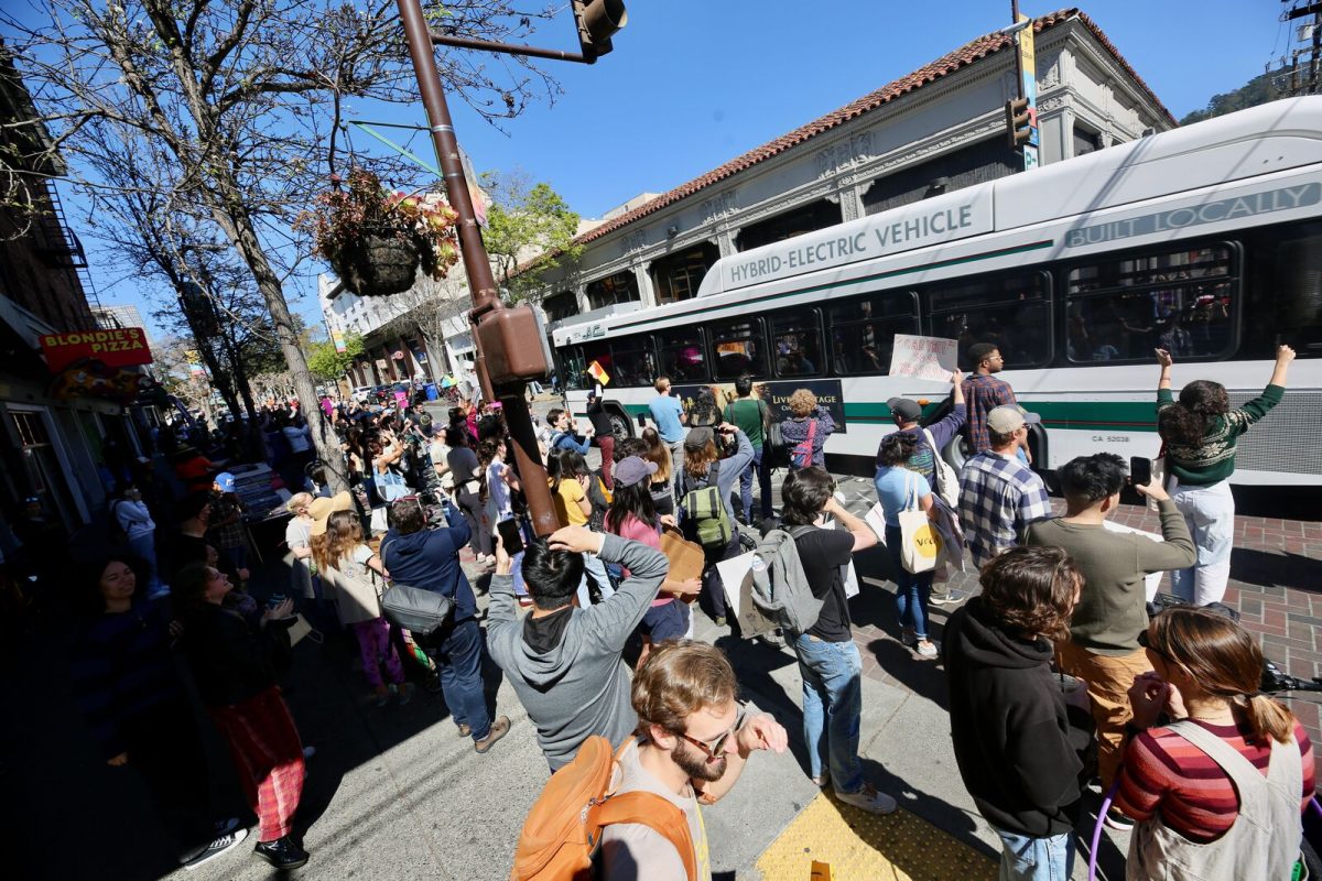 Dozens of demonstrators cheer a passing AC Transit bus at the intersection of Dwight Way and Telegraph Avenue near the UC Berkeley campus.
