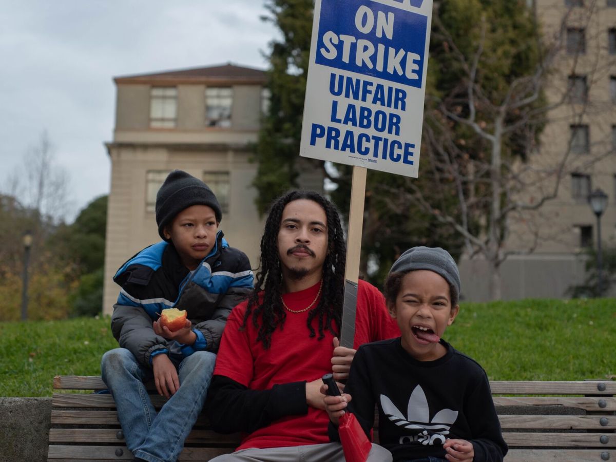 Vincente Perez, a striking fifth-year Cal doctoral student, photographed with his twin sons, Kaiyo (left) and Mikai (right), during a kid-friendly rally on Friday, Dec 9. Along with higher wages, the parents are asking for childcare subsidies and healthcare coverage for families.