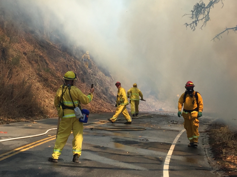 Firefighters on road with smoke in the background