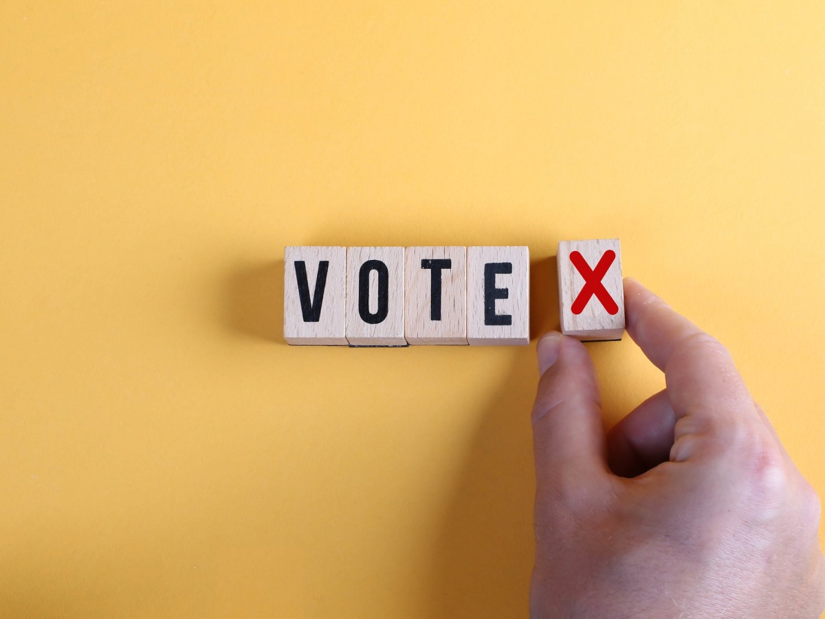 Concept of voting no or negative vote. Male hand placing wooden cube with no symbol next to the cubes with the word vote